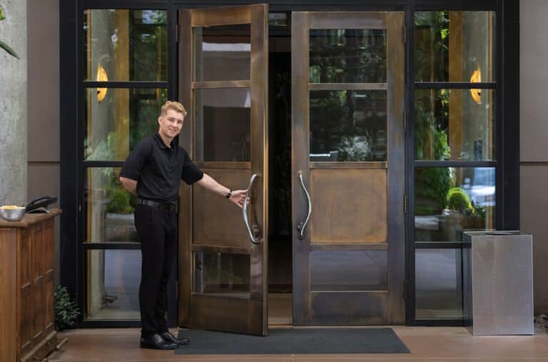 Bellhop standing at wooden reception desk of a downtown hotel.