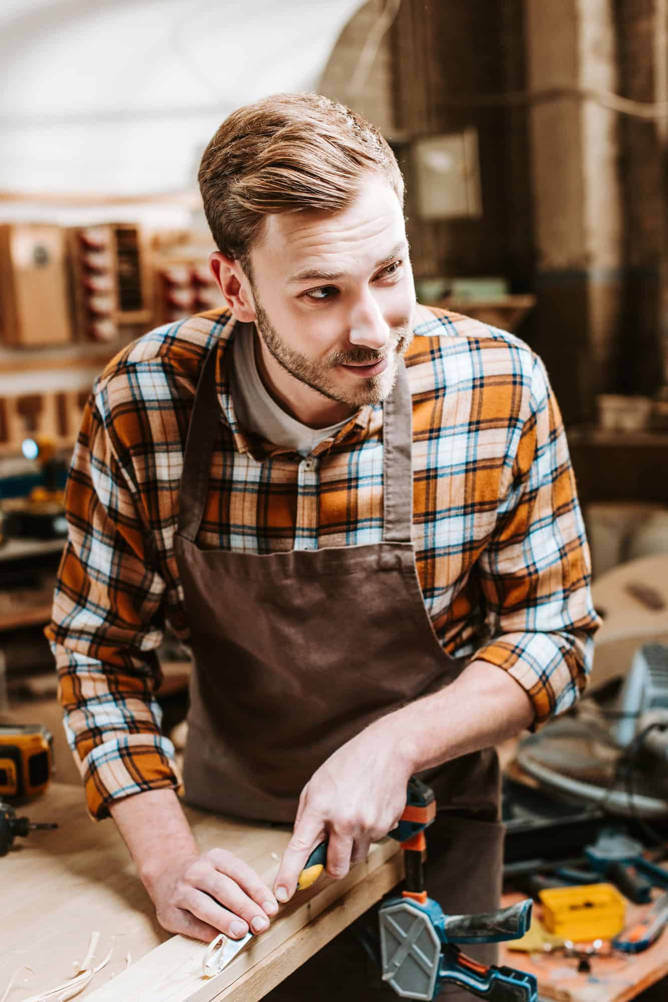 carpenter holding chisel while carving wood in workshop